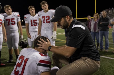 Athletic Trainer Inspecting Injured Player at Football Game